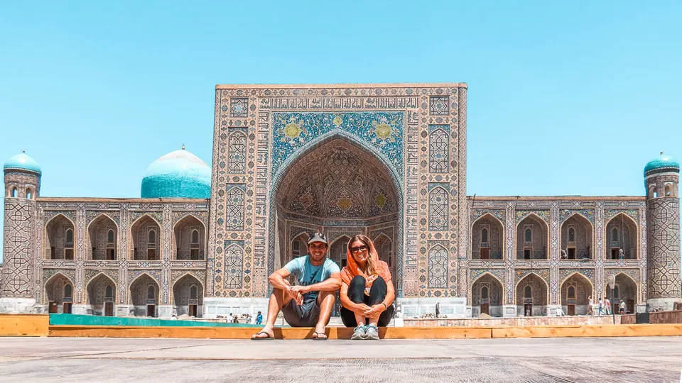 Juan y Flor sentados frente a una madrasa de azulejos en Samarcanda