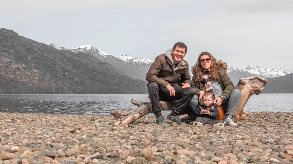 Juan y Flor con un bebé frente a un lago de la Patagonia rodeado de montañas
