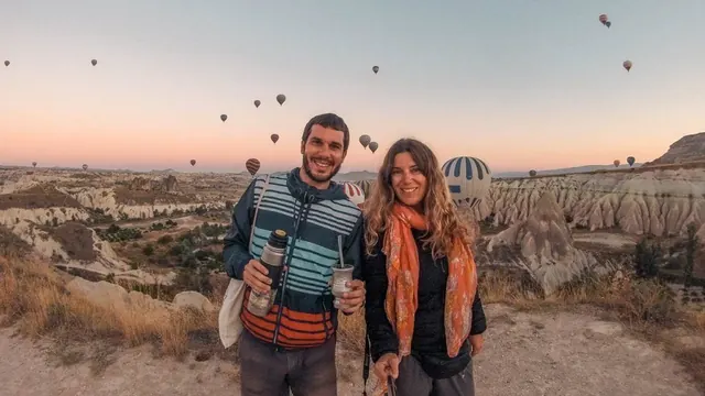 Juan y Flor con el mate en Capadocia, con globos aerostáticos de fondo